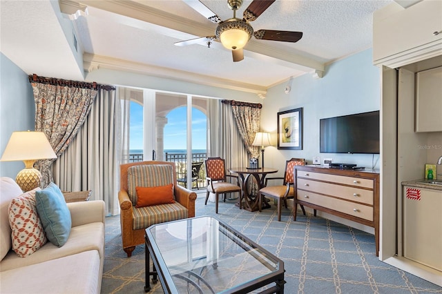 living room featuring a textured ceiling, ceiling fan, beamed ceiling, and dark colored carpet