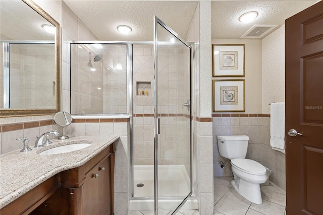 bathroom featuring tile walls, vanity, a textured ceiling, and toilet