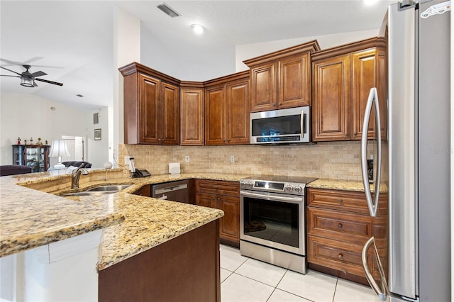 kitchen with sink, appliances with stainless steel finishes, light tile patterned floors, backsplash, and vaulted ceiling