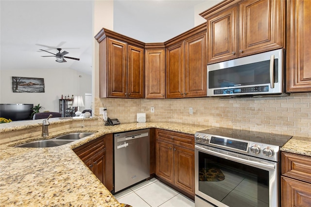 kitchen with stainless steel appliances, lofted ceiling, sink, backsplash, and light stone countertops