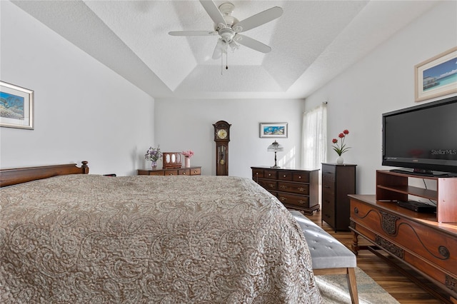 bedroom featuring a textured ceiling, dark wood-type flooring, ceiling fan, and a tray ceiling