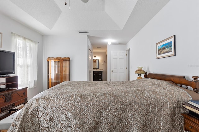 bedroom with ensuite bathroom, a textured ceiling, and ceiling fan