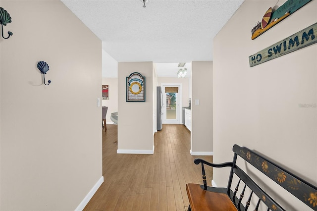 hall featuring a textured ceiling and light hardwood / wood-style flooring