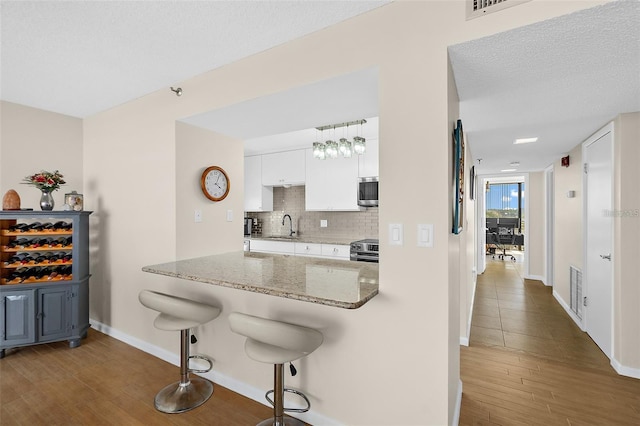 kitchen featuring white cabinets, a breakfast bar area, dark hardwood / wood-style floors, stone countertops, and stainless steel appliances