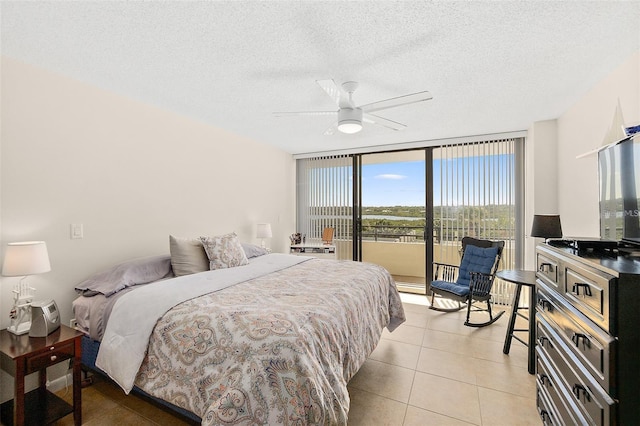 bedroom with access to exterior, light tile patterned flooring, expansive windows, a textured ceiling, and ceiling fan