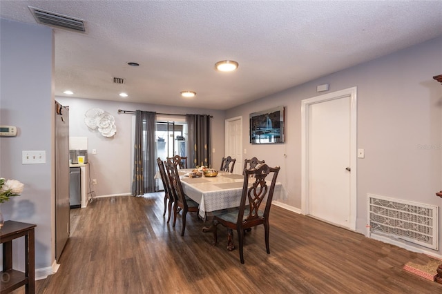 dining space with dark hardwood / wood-style floors and a textured ceiling