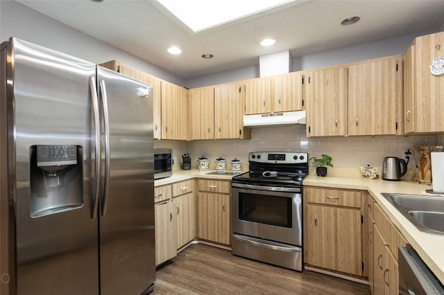 kitchen featuring tasteful backsplash, light brown cabinetry, appliances with stainless steel finishes, sink, and dark hardwood / wood-style floors