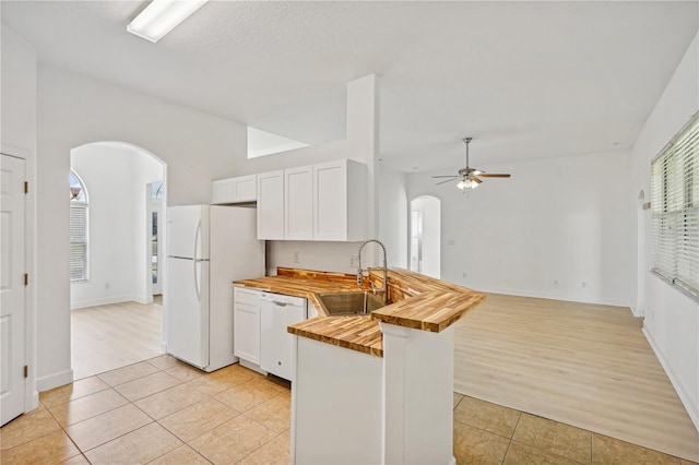 kitchen featuring butcher block counters, sink, light wood-type flooring, white cabinets, and white appliances