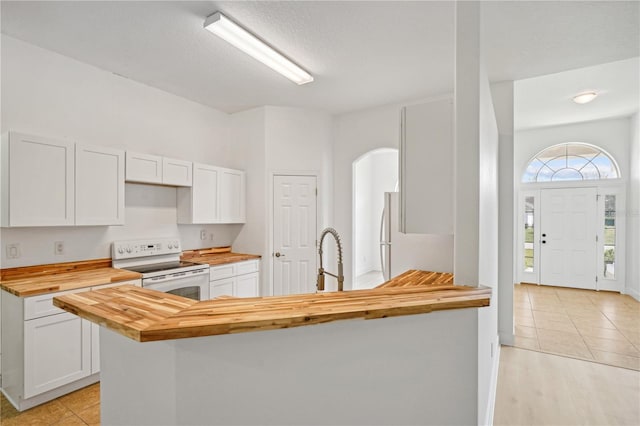 kitchen with white cabinets, light tile patterned flooring, wooden counters, sink, and white appliances