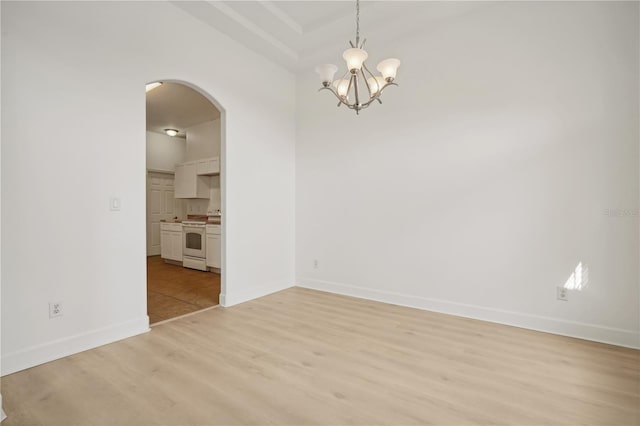 spare room with a notable chandelier and light hardwood / wood-style flooring