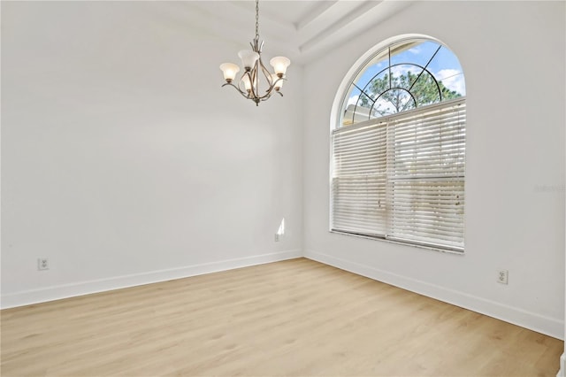 spare room featuring a chandelier and light hardwood / wood-style flooring