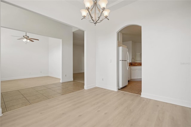 spare room featuring light hardwood / wood-style flooring and ceiling fan with notable chandelier