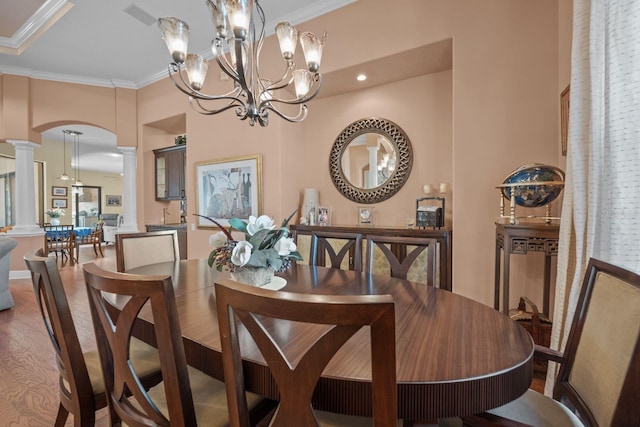 dining room featuring dark hardwood / wood-style floors, ornate columns, crown molding, and an inviting chandelier