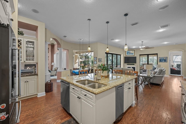 kitchen with a center island with sink, sink, stainless steel dishwasher, ceiling fan, and white cabinetry