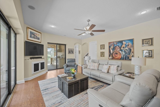 living room featuring a textured ceiling, light hardwood / wood-style floors, and ceiling fan