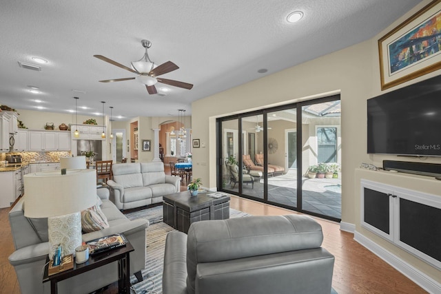 living room with a textured ceiling, light hardwood / wood-style floors, and ceiling fan