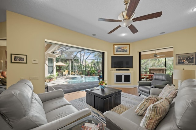 living room with ceiling fan, wood-type flooring, and a textured ceiling