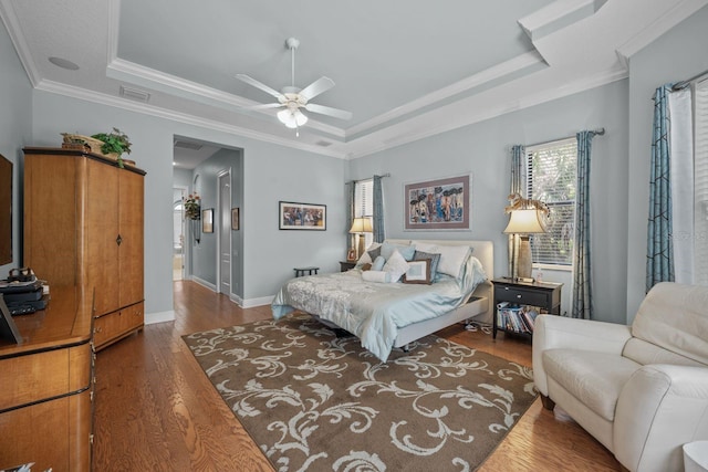 bedroom featuring a tray ceiling, ceiling fan, dark hardwood / wood-style floors, and ornamental molding