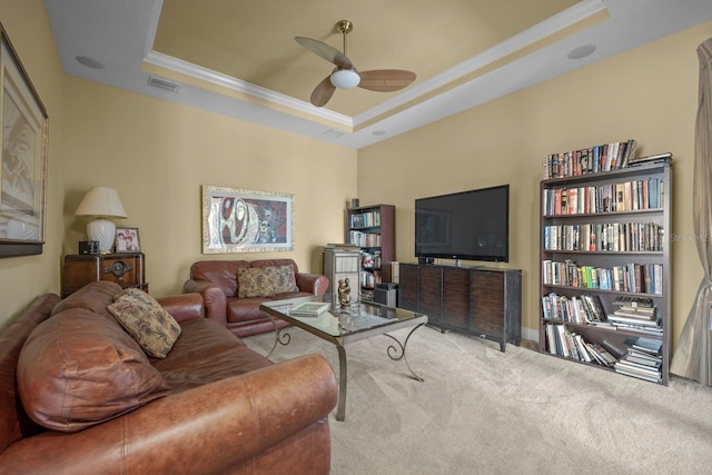 living room with carpet flooring, a raised ceiling, ceiling fan, and crown molding