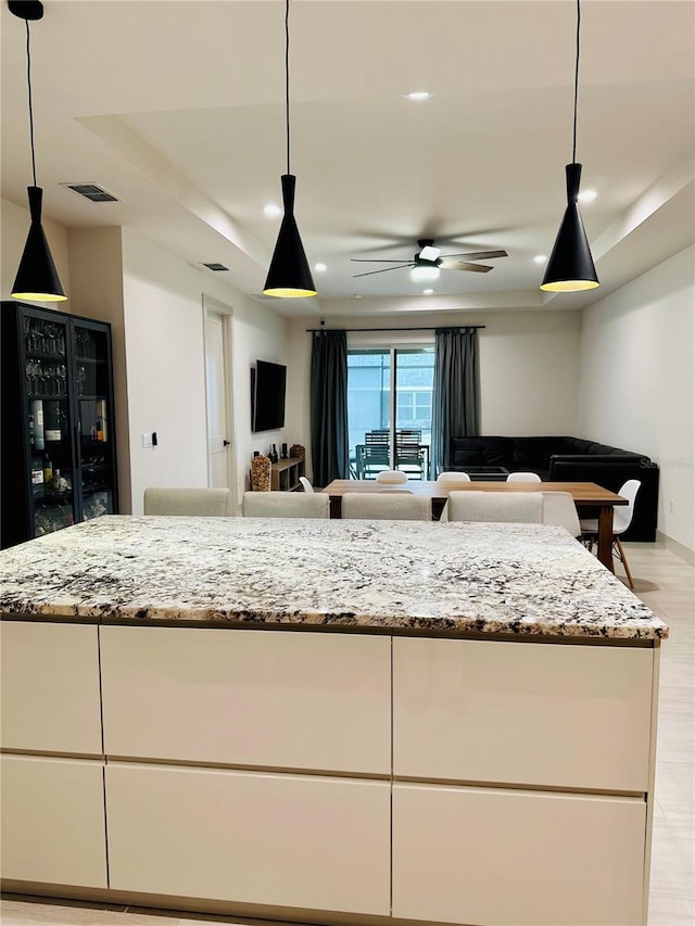 kitchen featuring light hardwood / wood-style floors, white cabinets, light stone countertops, and ceiling fan