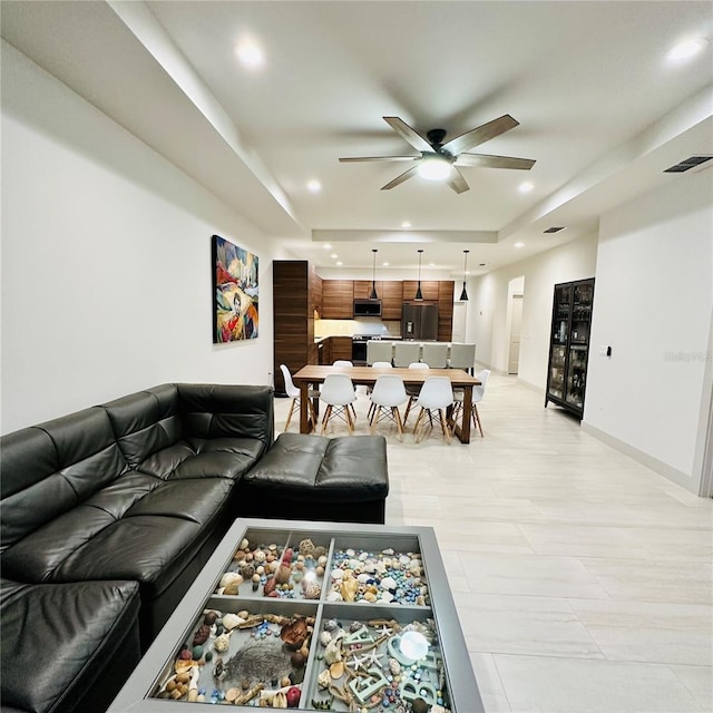 living room with ceiling fan and a raised ceiling