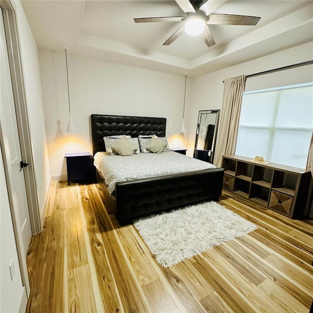 bedroom featuring hardwood / wood-style floors, a tray ceiling, and ceiling fan