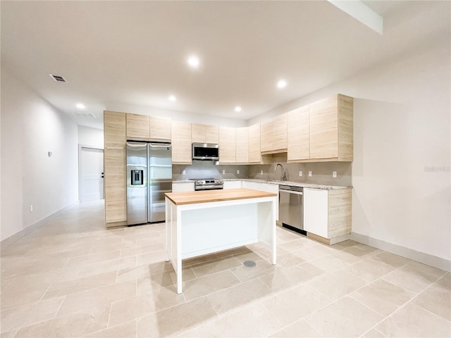 kitchen with light tile patterned floors, butcher block counters, stainless steel appliances, sink, and a center island