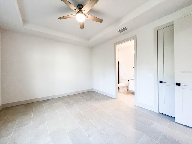 unfurnished room with ceiling fan, light tile patterned floors, and a raised ceiling