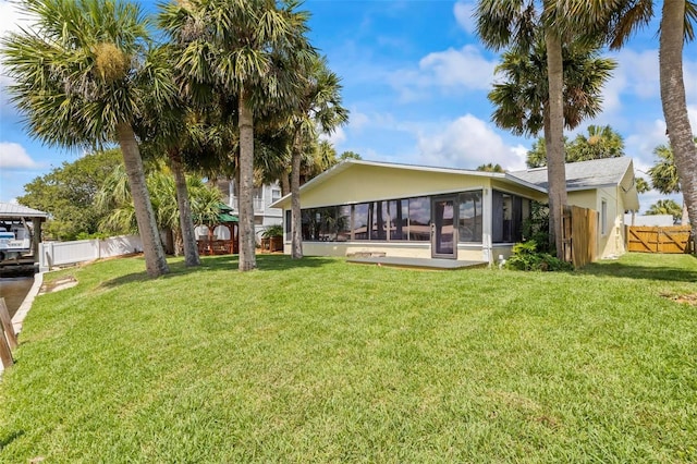 back of property with a lawn and a sunroom