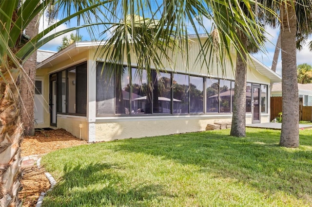 view of side of home featuring a sunroom and a yard