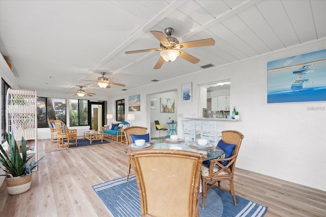 dining space featuring beam ceiling, light hardwood / wood-style flooring, and ceiling fan