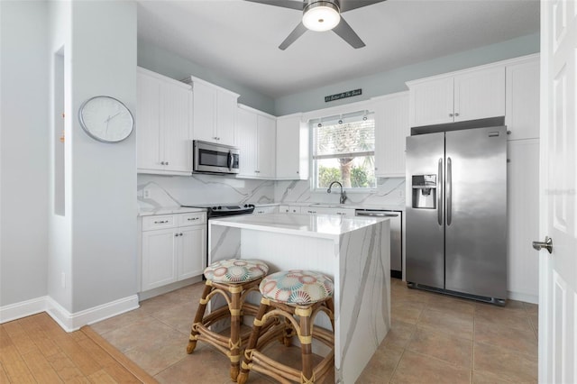 kitchen featuring a kitchen island, white cabinets, stainless steel appliances, and tasteful backsplash