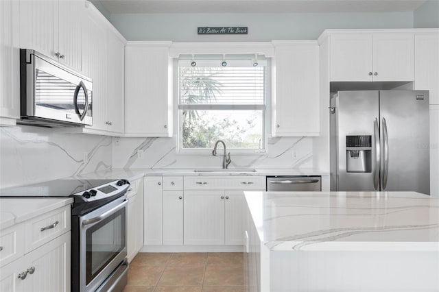 kitchen featuring sink, light tile patterned flooring, stainless steel appliances, white cabinets, and light stone counters