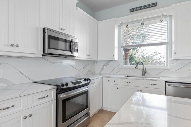 kitchen featuring white cabinetry, light stone countertops, appliances with stainless steel finishes, and sink