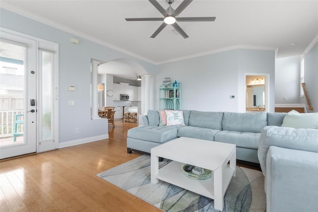 living room with crown molding, decorative columns, light hardwood / wood-style flooring, and ceiling fan