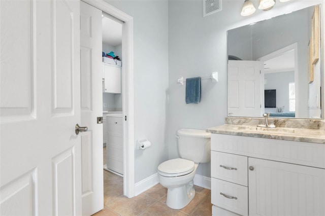 bathroom featuring vanity, toilet, washer / dryer, and tile patterned flooring