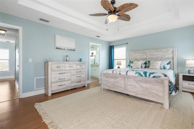 bedroom with ensuite bathroom, wood-type flooring, multiple windows, and ceiling fan