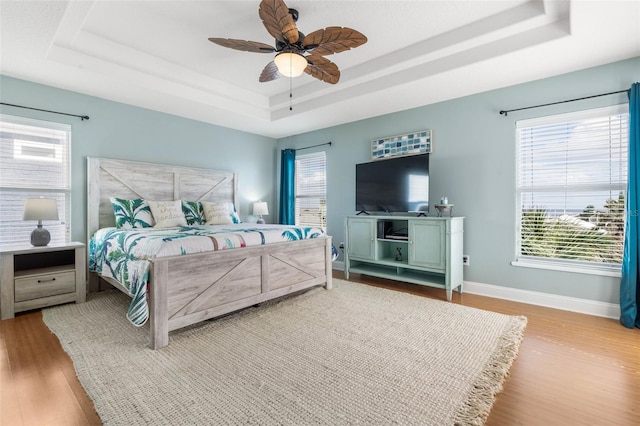 bedroom featuring ceiling fan, hardwood / wood-style flooring, and a tray ceiling