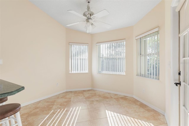 interior space featuring a textured ceiling, light tile patterned floors, and ceiling fan