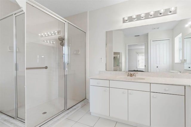 bathroom with vanity, a textured ceiling, a shower with shower door, and tile patterned floors