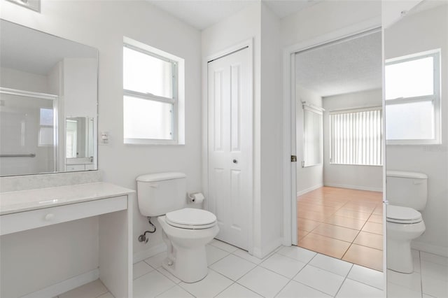 bathroom with vanity, a shower with shower door, toilet, and tile patterned flooring