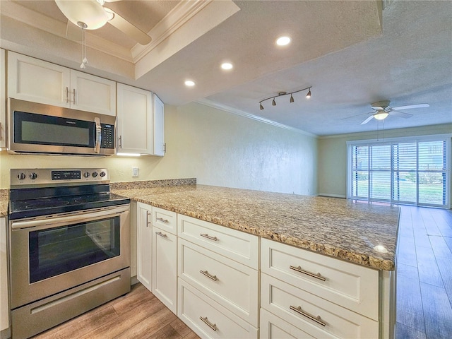 kitchen with appliances with stainless steel finishes, kitchen peninsula, white cabinetry, and light hardwood / wood-style floors