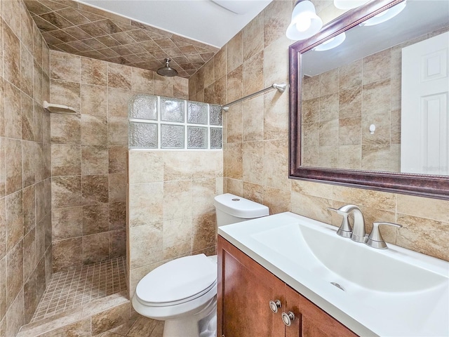 bathroom featuring a tile shower, tasteful backsplash, toilet, tile walls, and vanity