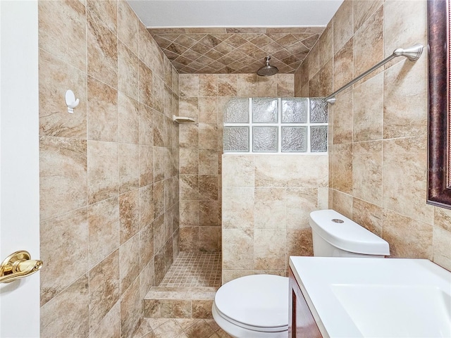 bathroom featuring vanity, a tile shower, and toilet