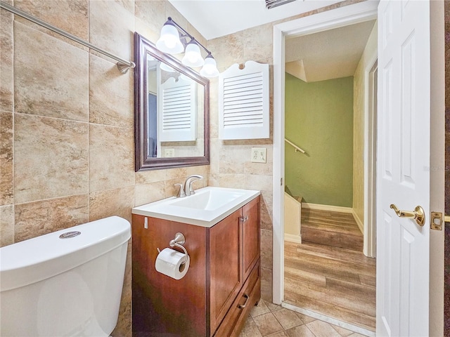 bathroom with tile walls, vanity, wood-type flooring, and toilet