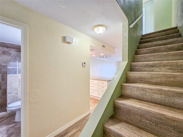 stairway featuring a textured ceiling and hardwood / wood-style flooring