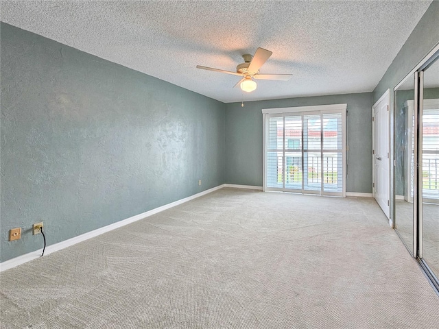 empty room featuring a textured ceiling, light colored carpet, and ceiling fan