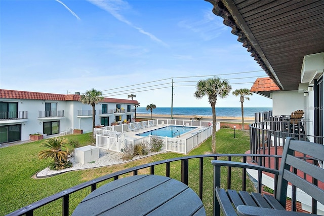 view of pool with a water view and a lawn