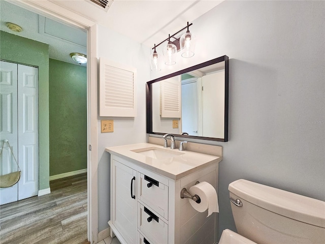 bathroom with toilet, vanity, and wood-type flooring