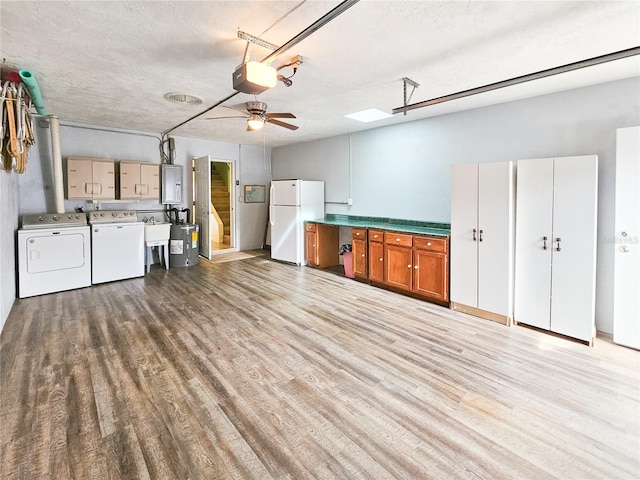 kitchen featuring washing machine and dryer, a textured ceiling, light hardwood / wood-style floors, white fridge, and electric panel